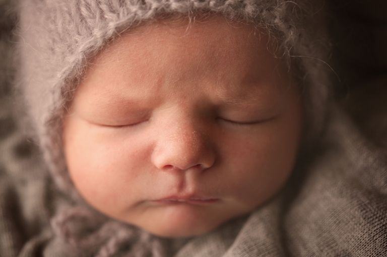 Beautiful close up picture of a newborn baby face with a newborn bonnet on
