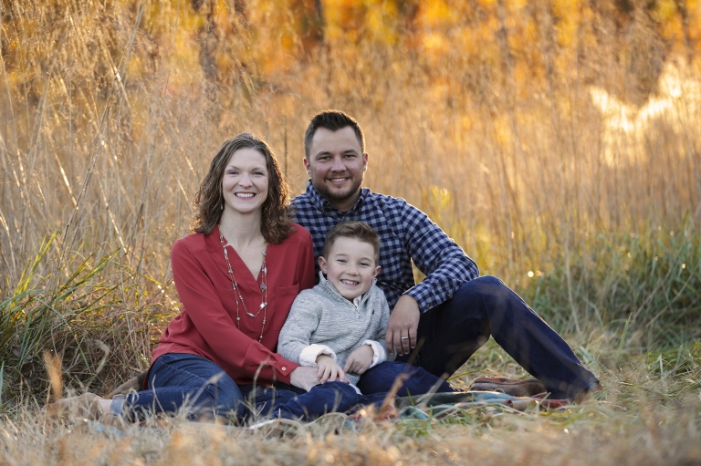 Family of three sitting down in a beautiful golden field