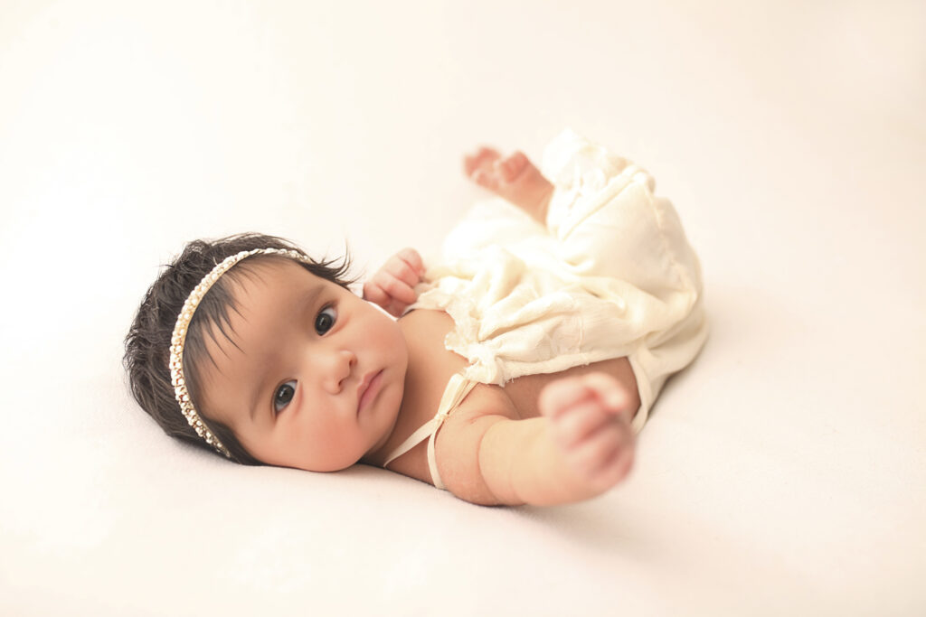 Baby girl wrapped in a cream swaddle during a newborn photography session in Raleigh, NC